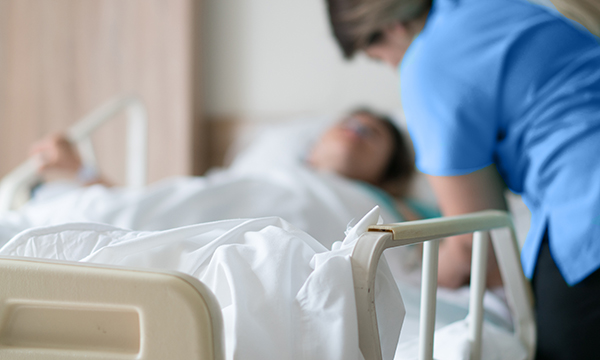 Patient death linked to lack of repositioning: patient in bed is tended to by nurse