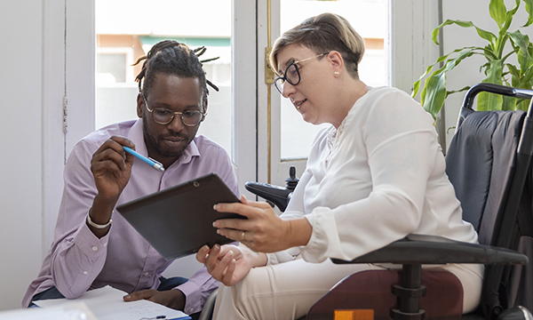 PIP assessor visits a claimant at home; they look at tablet screen together, the assessor makes notes