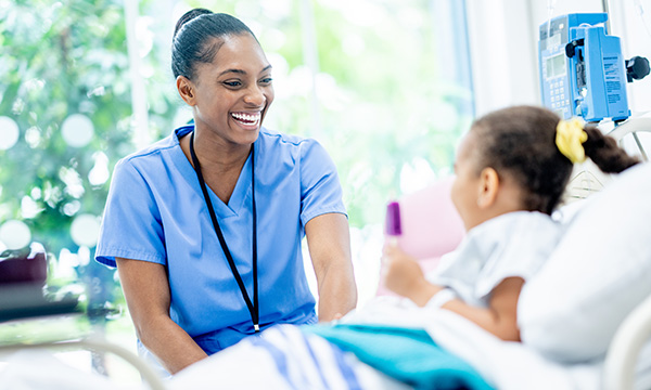 To address adverse childhood experiences changes to health, economic and gender inequalities as well as discrimination need to be faced up to. A nurse smiles and talks with a young girl in a hospital bed