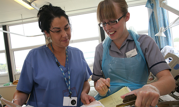 A practice assessor on a busy ward assesses the work of a nursing student on a clinical placement