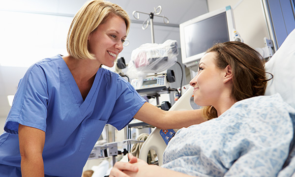 Kindness and compassion in nursing: a smiling nurse tends to a patient in a hospital bed