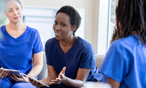 A band 7 nurse and team leader sits talking to her nursing team