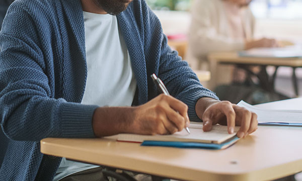 Nurse struck off for exam cheating: man writing notes during a written exam