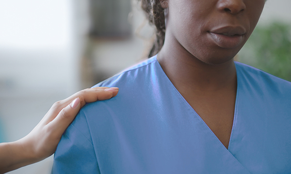 Nurse burnout: a hand placed on a nurse’s shoulder as a gesture of compassion and support