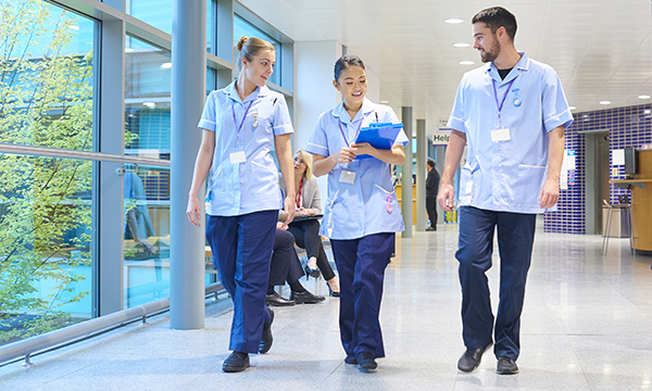 Foot health for nurses: three nurses walk in a hospital corridor