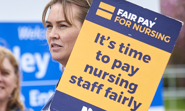 Pay reform: ‘nurses cannot keep fighting for scraps’; picture recalls 2023 strike action with nurse holding placard stating: 'It's time to pay nursing staff fairly'