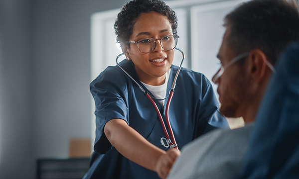 Performing chest auscultation: a nurse uses to stethoscope to examine a patient’s chest 