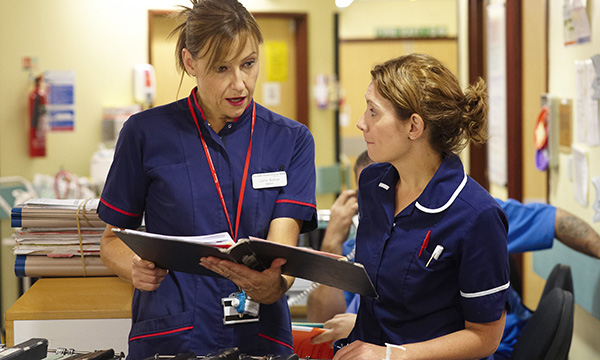 Matron careers opportunities for nurses: a senior nurse leader talks to a nurse colleague at ward nurses’ station