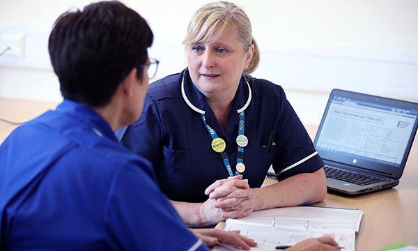 Reflective discussion: a senior nurse sits having a discussion with another nurse