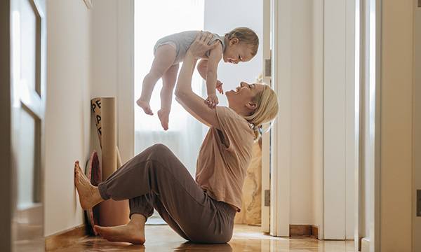 Return to work after maternity leave: a woman sits on the floor at home happily engaging with her young child