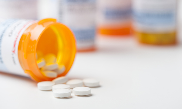 A medication bottle on its side with tablets spilling out of it