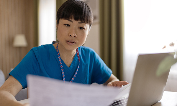 Nurse role re-banding: a nurse sits with her laptop, poring over paperwork