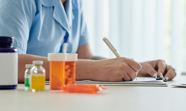 Medicines arranged on a table where a nurse is making notes