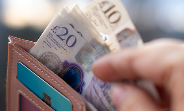 NMC fee rise: £10 and £20 notes being handled in brown wallet