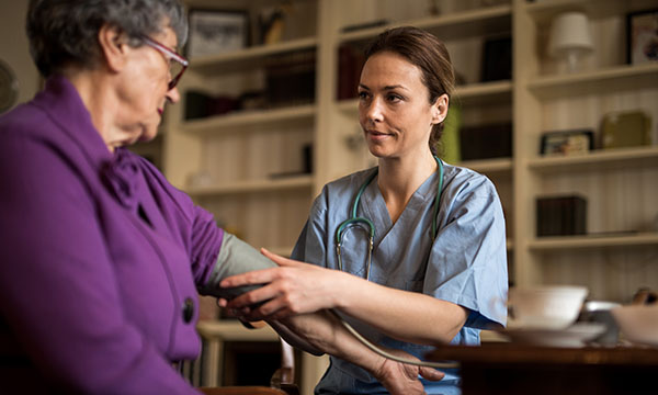 district nurse take woman's blood pressure