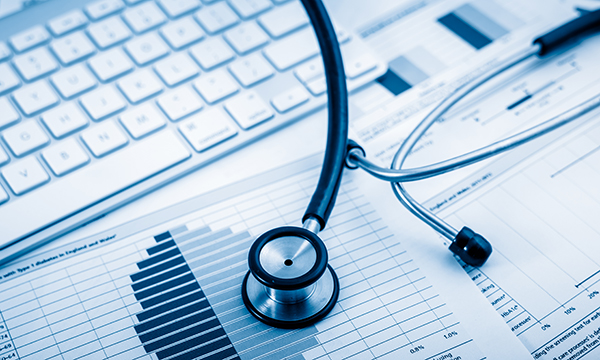 A stethoscope spread across a book of graphs in front of a computer keyboard