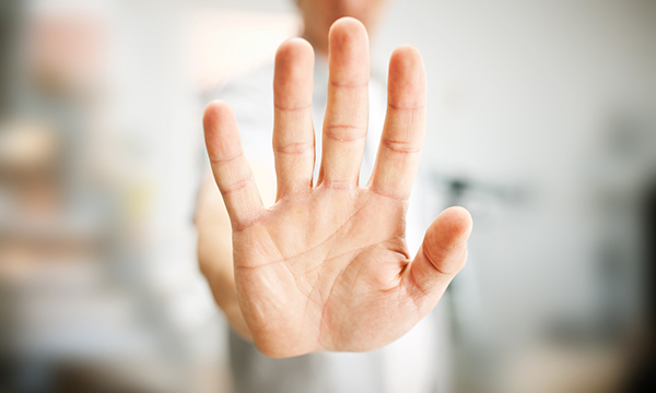 A figure with an open-palmed had raised to protect from aggression 