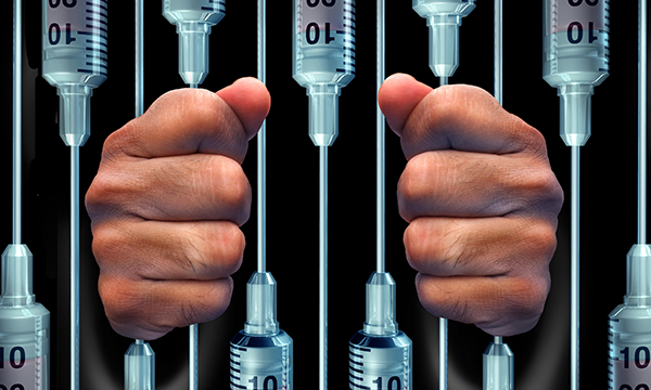 hands around syringes arranged like prison bars