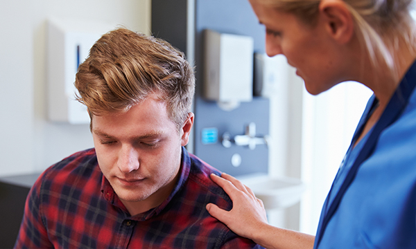 A nurse puts a reassuring hand on the shoulder of a patient
