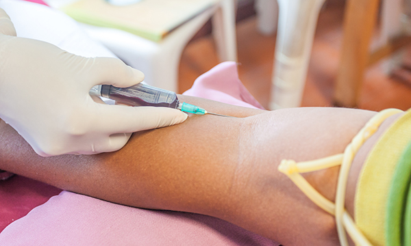 Hypodermic needle being inserted into patients arm at a clinic