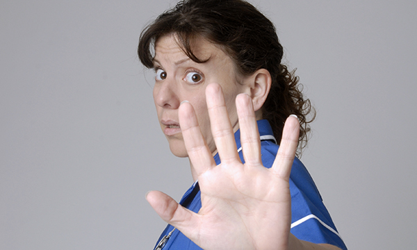 frightened nurse holds hand up in self-defence