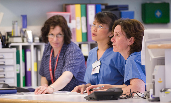 Three busy nurses at nursing station