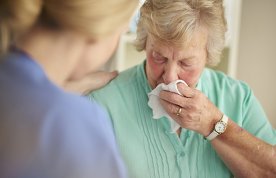 woman dabs her face with a tissue as nurse talks to her