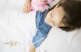 Picture shows a child lying in a hospital bed with an IV line attached to her arm