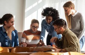 Group of young people in a huddle as if planning how to execute a task, illustrating group work in nursing education