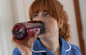 Picture shows a nursing student in uniform sipping from their own refillable water bottle during a shift