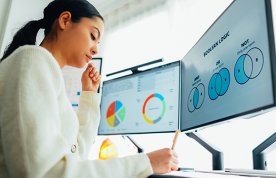 Research terminology and images on two computer screens, as a nursing student sits at a desk studying