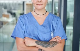Uniform policy for nursing students: a nurse stands with arms folded showing a large tattoo on her arm