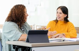 Action plans for nursing students: a student sits at a desk with an instructor, listening as a point is explained