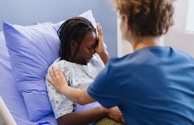 Trauma-informed nursing care: nurse comforts a weeping woman in a hospital bed