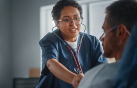 Performing chest auscultation: a nurse uses to stethoscope to examine a patient’s chest 