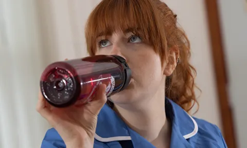 Picture shows a nursing student in uniform sipping from their own refillable water bottle during a shift