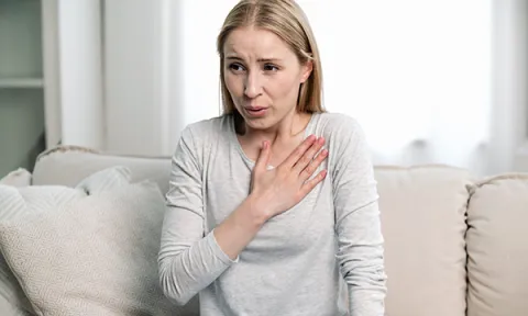 Nurses with long-COVID: a woman clutches her chest due to shortness of breath, a common symptom of long-COVID
