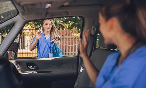 Community nursing as a newly registered nurse: a young nurse waves to a community nursing colleague as she drives away in a car