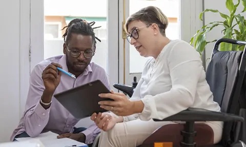 PIP assessor visits a claimant at home; they look at tablet screen together, the assessor makes notes