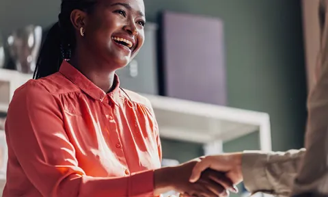 Nurse promotion: a smiling nurse shakes the hand of an interviewer as she introduces herself at the start of a job interview