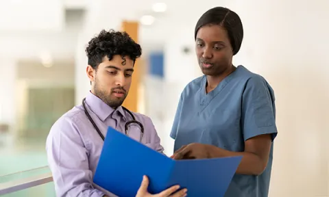 Escalating patient deterioration: nurse and doctor confer over patient notes