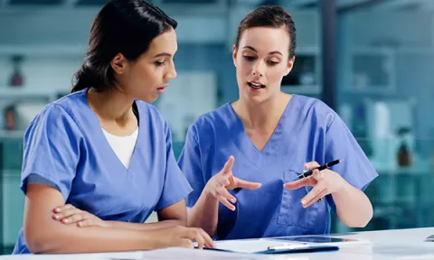 Asking for help as a nurse: a nurse gestures as she explains a point to a colleague