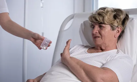 Patient in a hospital bed gestures to refuse her prescribed drugs