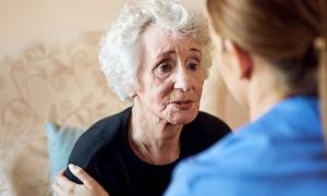 More than 1.4 million older people living in the UK report that they are often lonely: a nurse comforts and talks to an older woman