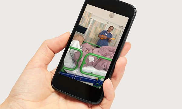 Hand holds phone showing video of singing nurse Beth Porch at Great Ormond Street Hospital