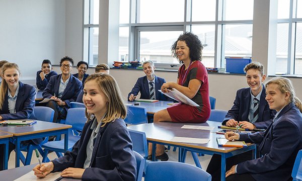 Image shows school teacher interacting with young people in a classroom lesson