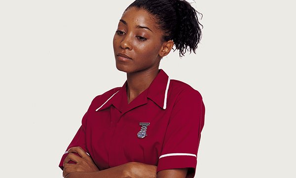 nurse stands with her arms folded, looking worried