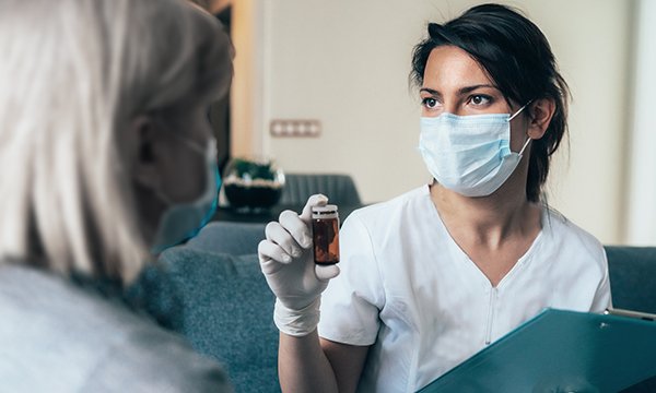 care home nurse administers care to resident wearing a face mask as precaution during Covid-19 pandemic