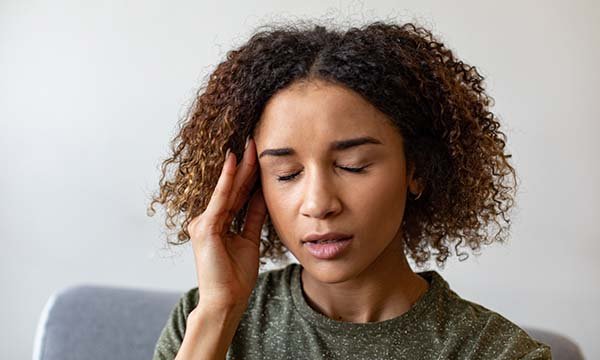 Picture shows a woman holding her head