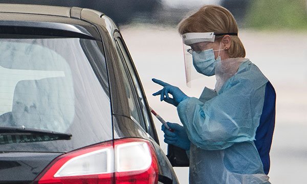 Picture shows a medic standing next to a car conducting a COVID-19 test at a temporary testing centre at Watford General Hospital